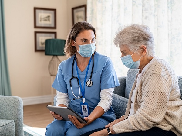 Nurse explaining therapy to senior woman at home visit